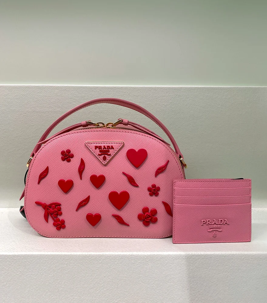 Unedited fashion product image of a pink handbag and wallet shot against a store setup.