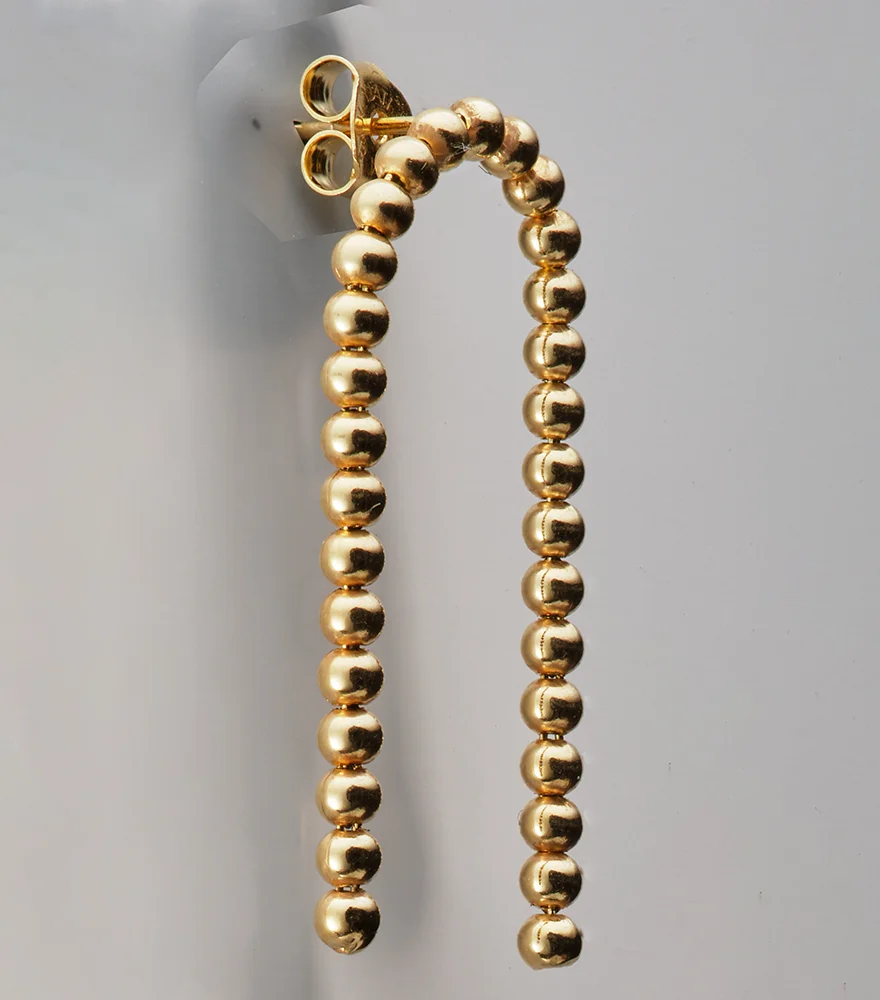 Original photo of golden earring on plastic display with reflections and shadows.