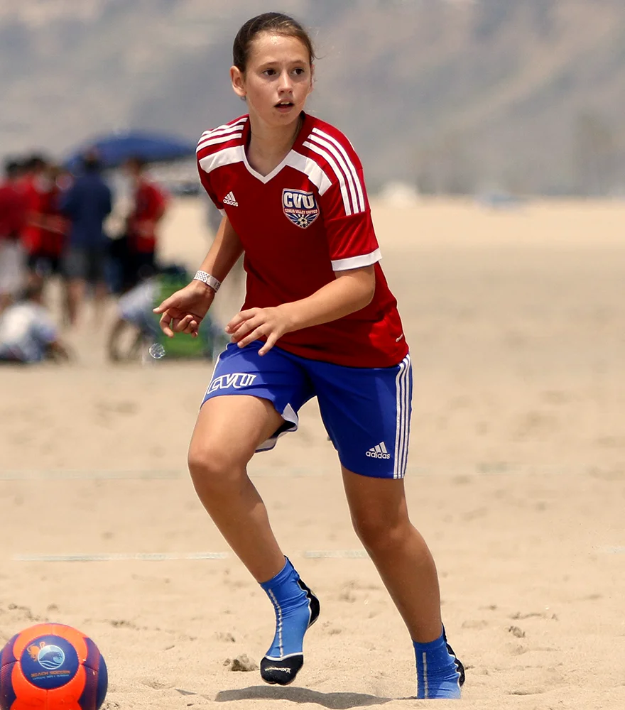 Original image of a soccer player in red gear on beach background.