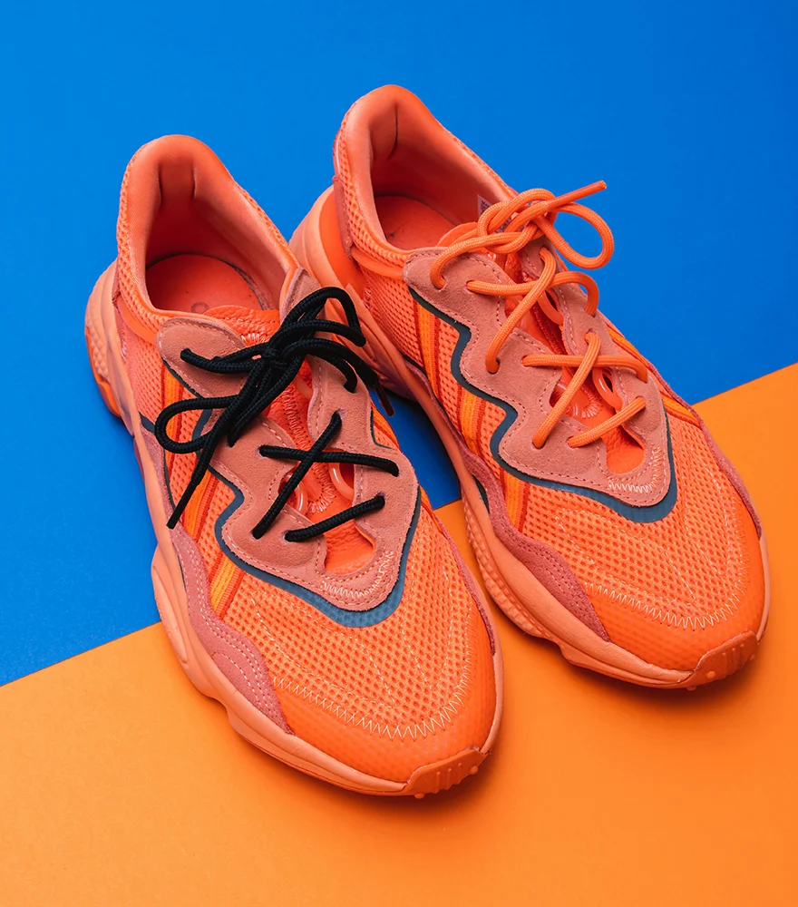 Orange sneakers placed on dual-tone blue and orange background.