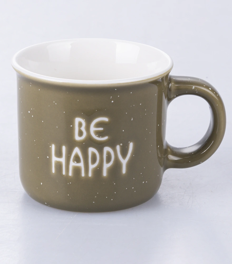 Ceramic mug with 'Be Happy' text on a white studio surface.