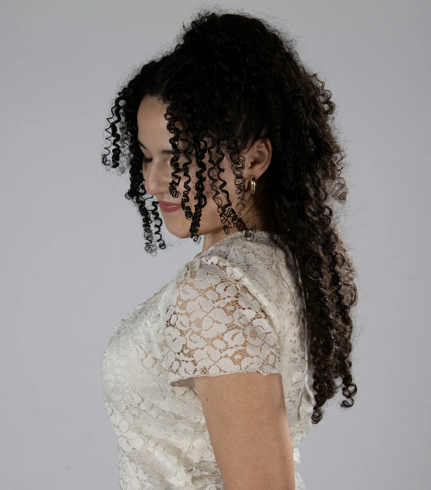 Original portrait of a woman with naturally curly hair and lace dress on a gray background.