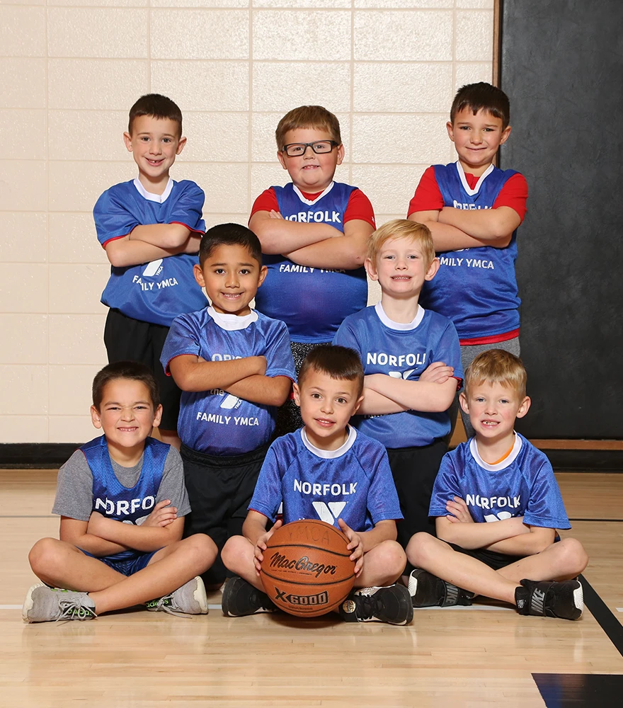 Youth basketball team posing inside a gym with original wall background.