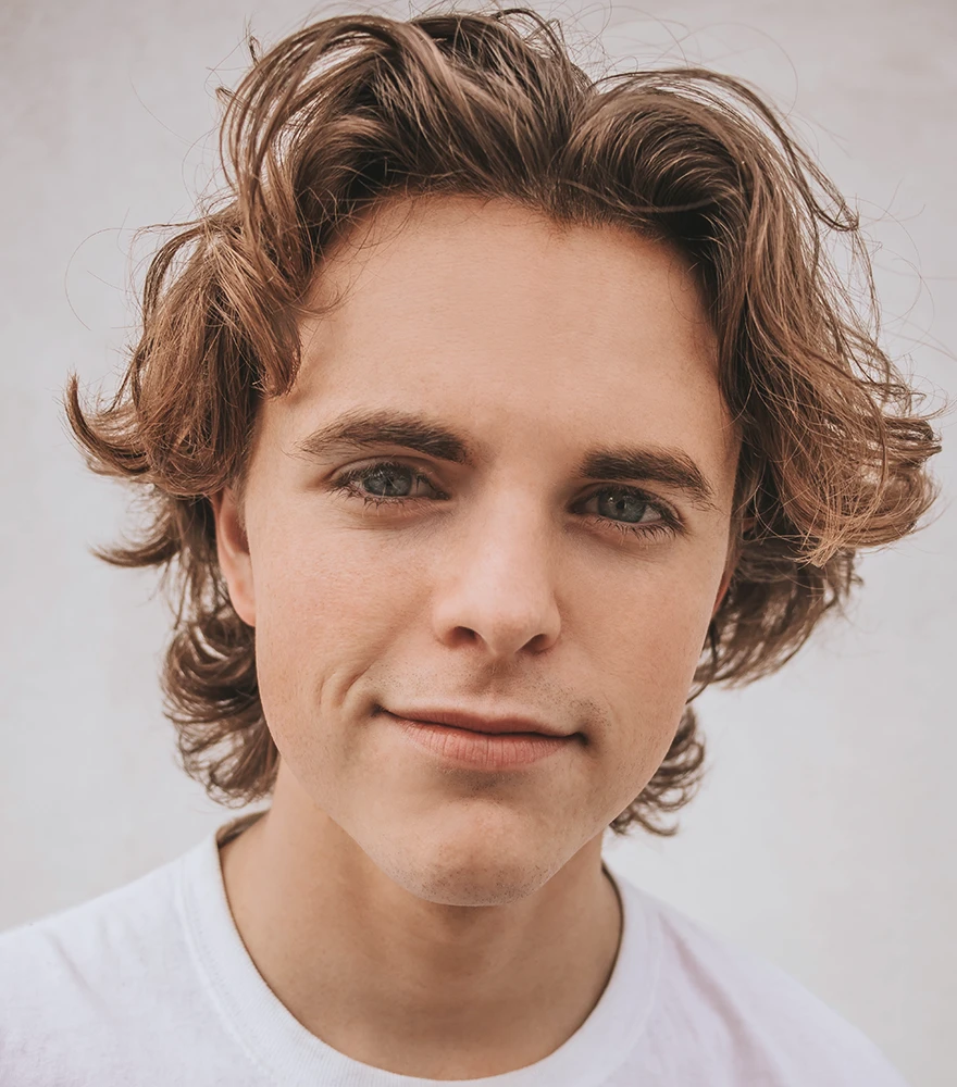 Edited close-up of a young man with smoother skin and natural tone, preserving realistic look.