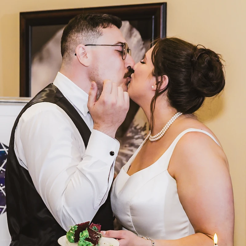 Enhanced wedding moment of bride and groom kissing during cake cutting.