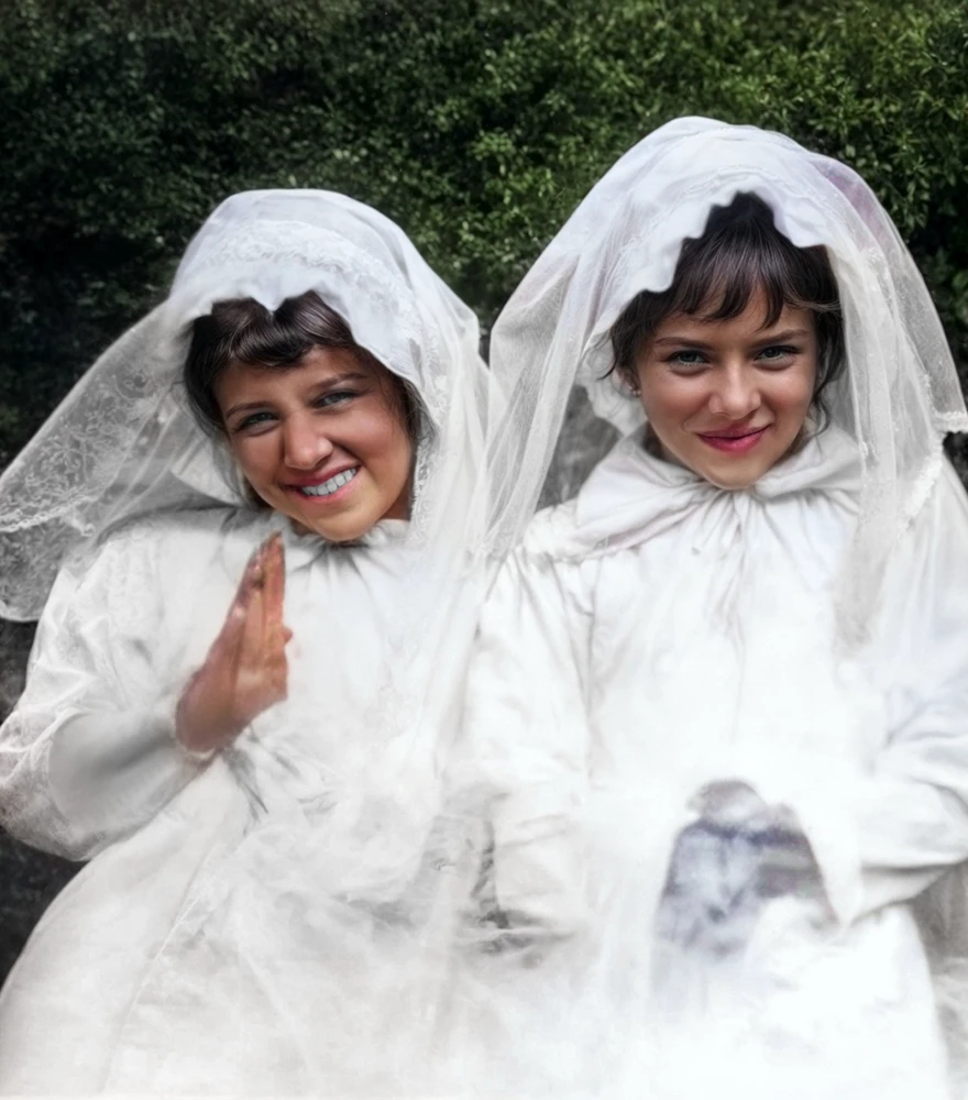 Restored and colorized photo of two young girls in white veils, smiling with natural skin tones and vibrant details.