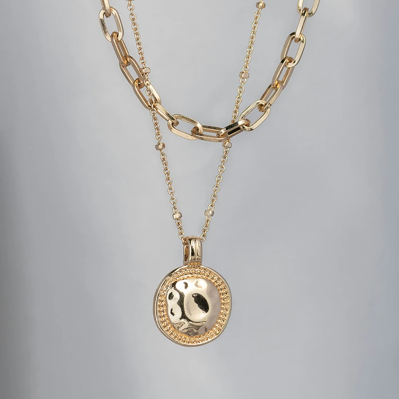 Original photo of gold layered necklaces placed against a light grey background.