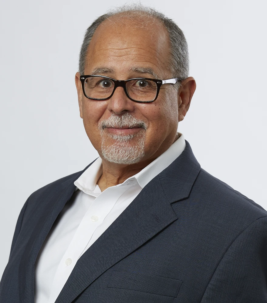 Corporate headshot of a man with natural lighting and visible skin texture.