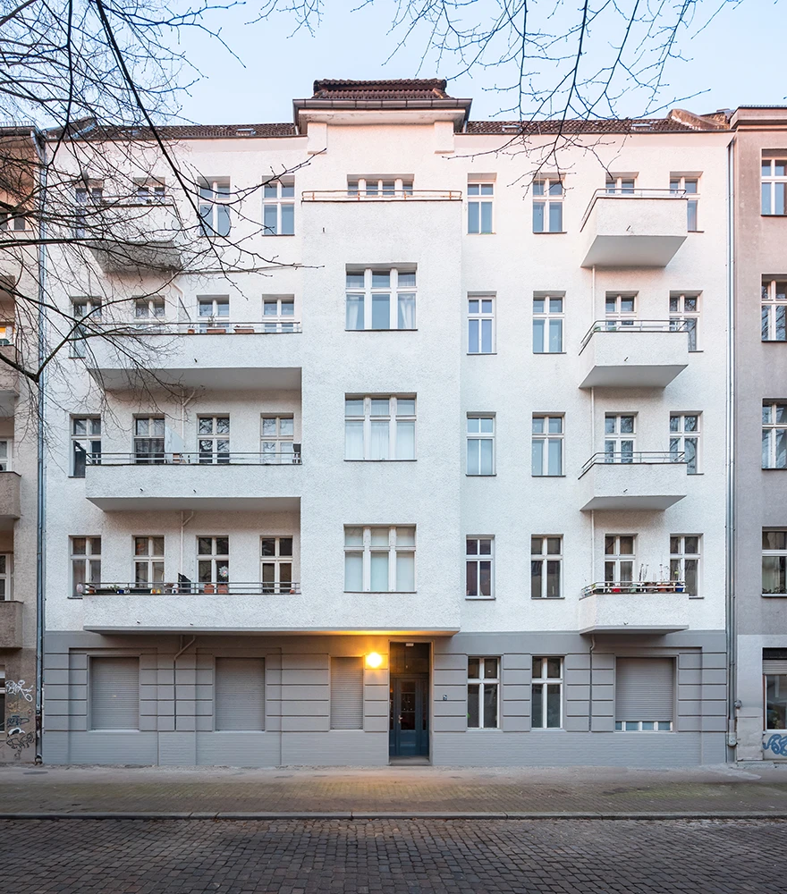 Building exterior with open balcony doors and inconsistent window views.